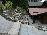 Paver pathway leading to stone steps in front of rock retaining wall