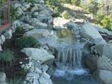 Meandering water feature of natural boulders adding ambiance